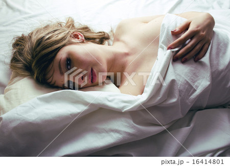 pretty blond woman laying in bed on white shits, sexy look 16414801