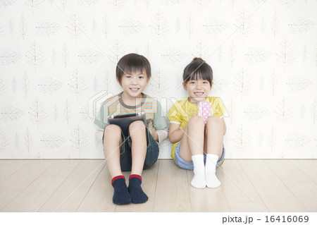 壁にもたれて座る男の子と女の子の写真素材