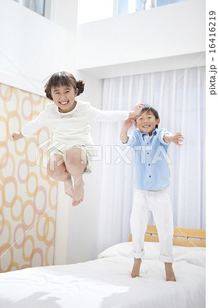ベッドでジャンプして遊ぶ子供たちの写真素材