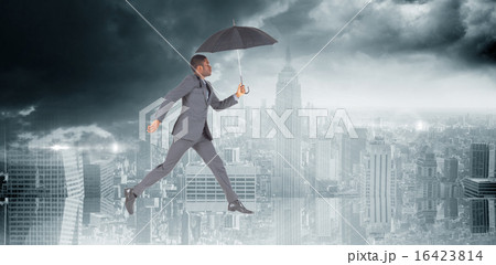 Composite image of businessman walking and holding umbrella 16423814