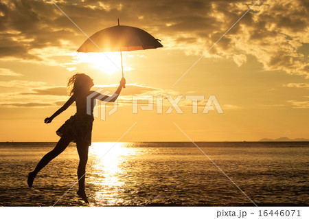 woman with an umbrella jumping on the beach woman with an umbrella jumping on the beach 16446071