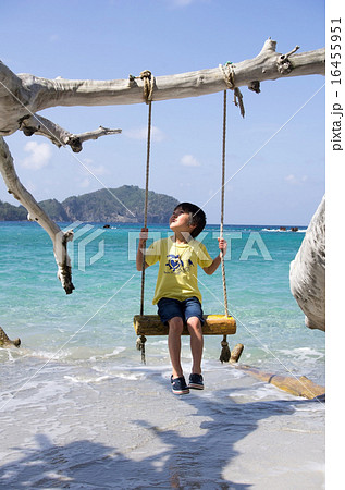 ブランコに座る子供と境浦海岸の背景 父島 の写真素材