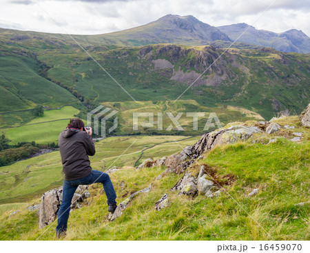 美しい山岳自然風景をカメラで撮影する男性の写真素材
