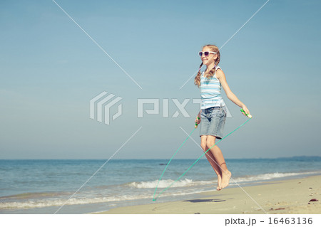 teen girl  jumping on the beach at blue sea shore  16463136