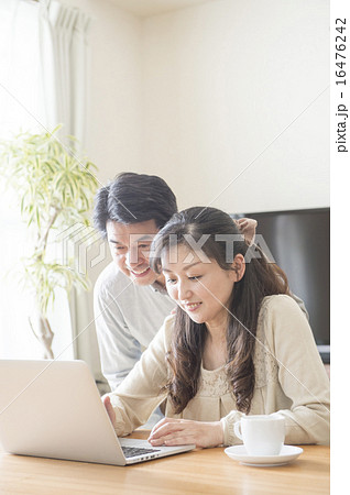 リビングでパソコンを見る中年夫婦 16476242