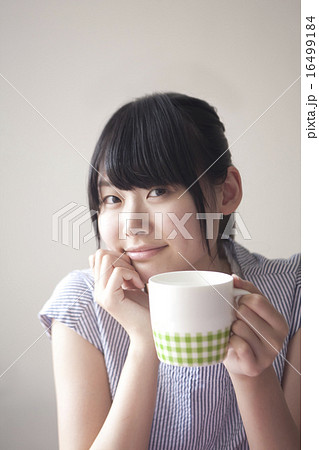 カフェでコーヒーカップを手に持つ女性の写真素材
