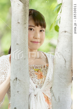 初夏の森林でリラックスする若い女性 16530011