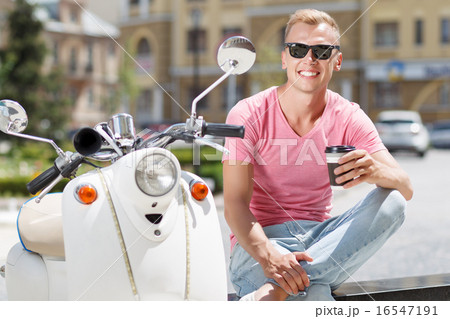 Handsome man sitting with coffee near his scooter  16547191