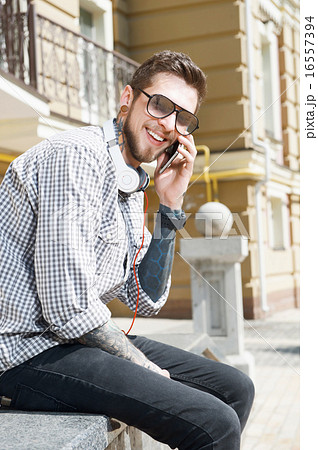 Handsome young man is telephoning in city 16557394