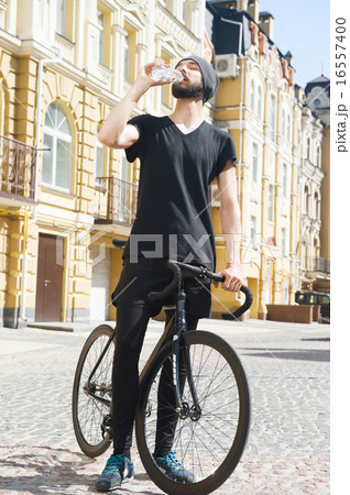 Cheerful young man is thirsty after cycling  16557400