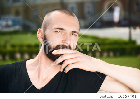 Attractive young hipster guy is having rest outdoors 16557401