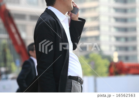 携帯（ガラケー）で話す男性サラリーマンの画像 16562563