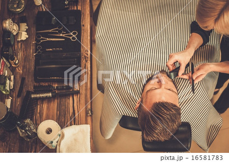 Client during beard and moustache grooming in barber shop 16581783