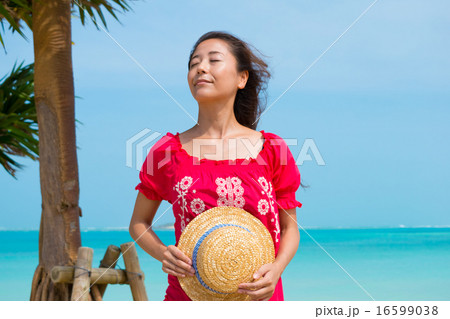 沖縄の海を眺める麦わら帽子を持つ女性 1 の写真素材