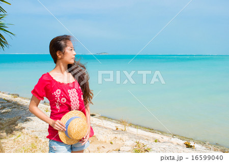 沖縄の海を眺める麦わら帽子を持つ女性 3 の写真素材