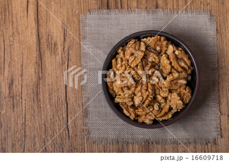 Shelled walnuts in bowl on wooden background 16609718