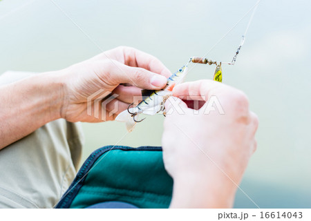 Angler fixing lure at hoof of fishing rod 16614043