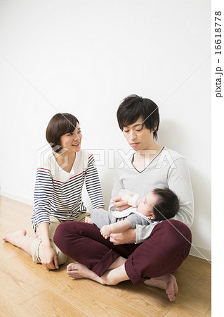 赤ちゃんにミルクをあげるお父さんとお母さんの写真素材