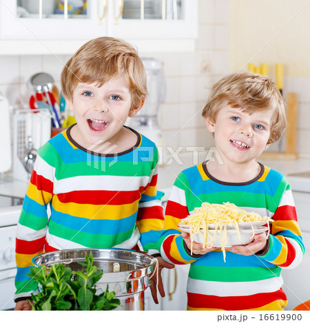 Two little kid boys eating spaghetti in domestic kitchen. 16619900