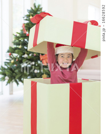 大きなプレゼントボックスから顔を出す女の子の写真素材