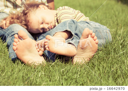 Father and son sitting on the grass at the day time. Father and son sitting on the grass at the day time. 16642970