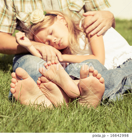 Father and daughter sitting on the grass at the day time. 16642998