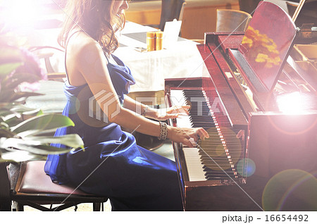 グランドピアノを弾いているドレスの女性の写真素材
