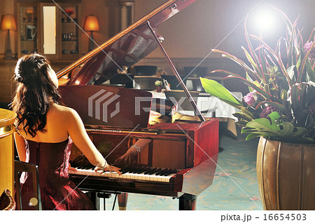 グランドピアノを弾いているドレスの女性の写真素材