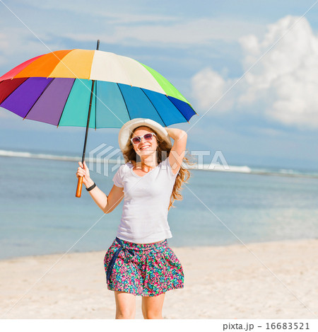 Cheerful young girl with rainbow umbrella having fun on the beach Cheerful young girl with rainbow umbrella having fun on the beach 16683521