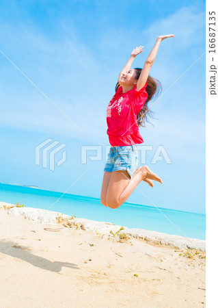 沖縄のビーチでジャンプする若い女性の写真素材