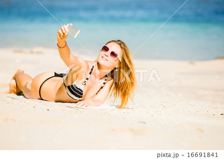 Sexy happy blond young female in sunglasses taking selfie on the beach enjoying summer holidays Sexy happy blond young female in sunglasses taking selfie on the beach enjoying summer holidays 16691841