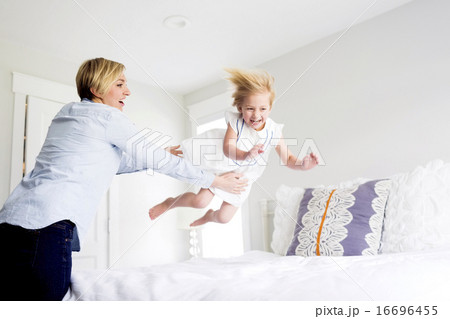 Woman playing with girl (2-3) in bedroom 16696455