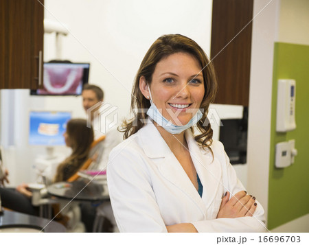 Portrait of dentist with colleague and patient in background 16696703