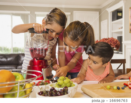 Children (2-3, 6-7, 8-9) preparing fruit cocktails 16696763