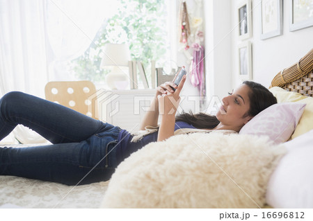 Teenage girl (14-15) texting in bedroom Teenage girl (14-15) texting in bedroom 16696812