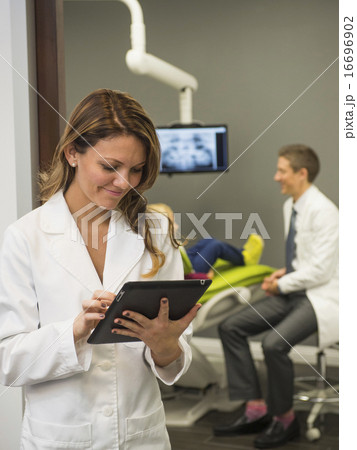 Portrait of dentist with colleague and patient (8-9) in background 16696902