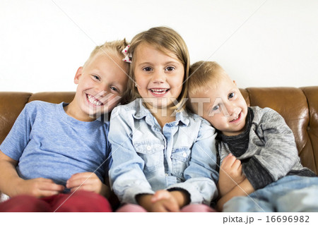 Smiling children (2-3, 4-5) sitting on sofa  16696982