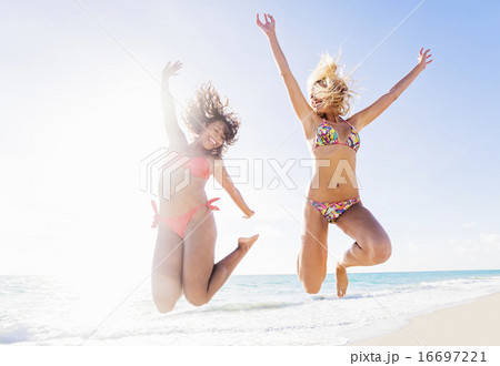 Female friends jumping on beach Female friends jumping on beach 16697221