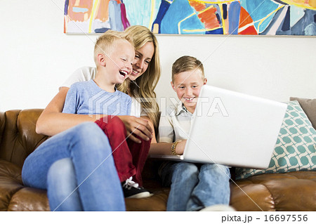 Mother with children (4-5, 6-7) using laptop on sofa 16697556