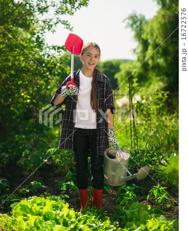 girl posing at garden with spade and watering can 16722576