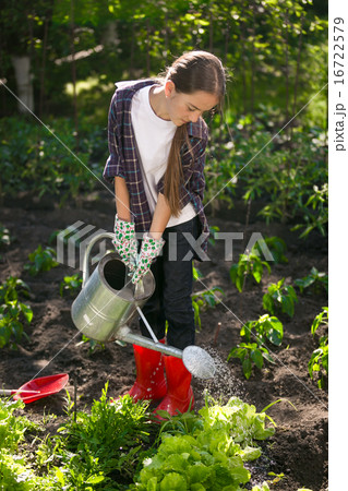 Cute girl watering garden with watering can Cute girl watering garden with watering can 16722579