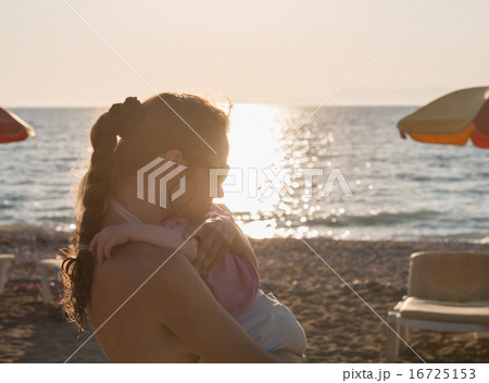 Silhouette of mother hugging baby on lonely beach Silhouette of mother hugging baby on lonely beach 16725153