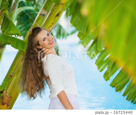 Happy young woman among tropical palms Happy young woman among tropical palms 16725440