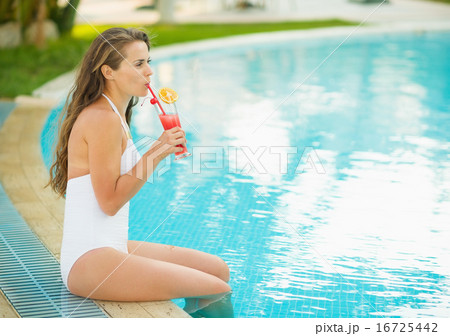 Happy young woman sitting at pool and drinking cocktail Happy young woman sitting at pool and drinking cocktail 16725442