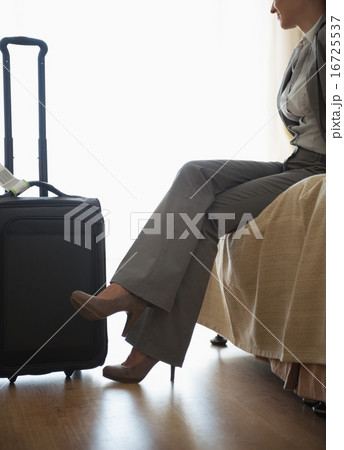 Tired business woman sitting on bed in hotel room after trip 16725537