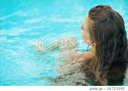 Young woman sitting in pool . rear view 16725592
