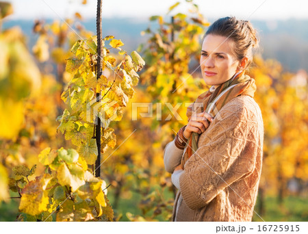Portrait of thoughtful young woman standing in autumn vineyard 16725915