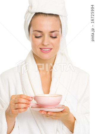 Happy young woman in bathrobe enjoying cup of tea Happy young woman in bathrobe enjoying cup of tea 16725994