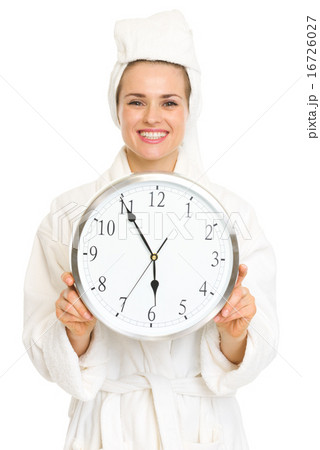 Smiling young woman in bathrobe holding clock Smiling young woman in bathrobe holding clock 16726027