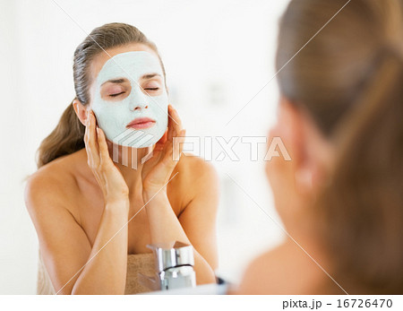 Young woman applying facial mask in bathroom 16726470